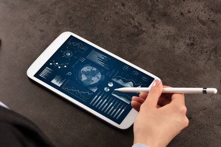 Business woman verifying reports on tablet with pencil in business suitの写真素材