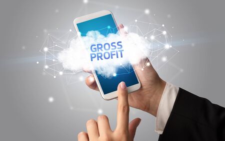 Female hand touching smartphone with GROSS PROFIT inscription, cloud business conceptの写真素材