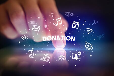 Finger touching tablet with drawn social media icons and DONATION inscription, social networking conceptの写真素材