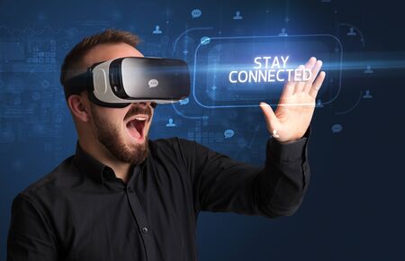 Businessman looking through Virtual Reality glasses with STAY CONNECTED inscription, social...
