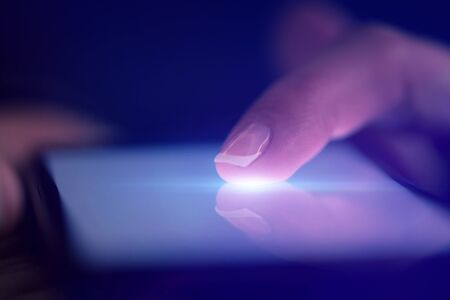 Finger touching phone with dark background with copyspaceの写真素材