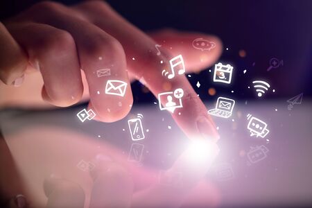 Finger touching tablet with hologram application icons and dark background