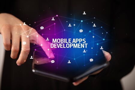 Businessman holding a foldable smartphone with MOBILE APPS DEVELOPMENT inscription, new technology conceptの写真素材