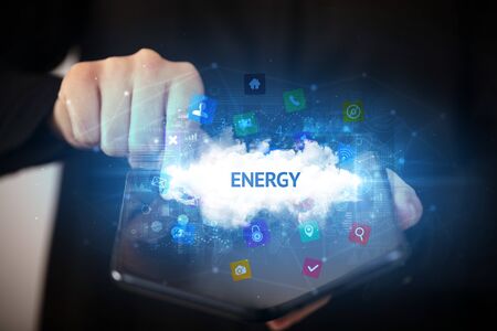 Businessman holding a foldable smartphone with ENERGY inscription, technology conceptの写真素材