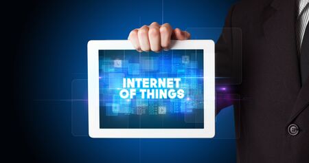 Young business person working on tablet and shows the inscription: INTERNET OF THINGSの写真素材