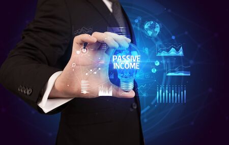 Businessman holding lightbulb with PASSIVE INCOME inscription, Business idea conceptの写真素材