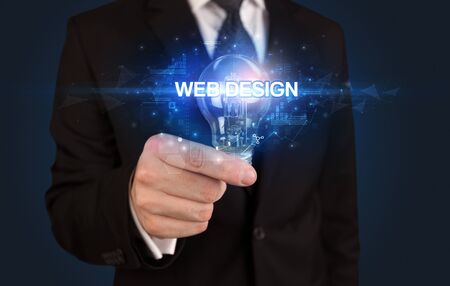 Businessman holding light bulb with WEB DESIGN inscription, innovative technology conceptの写真素材