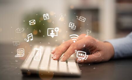Business woman hand typing on keyboard with drawn application icons aroundの写真素材