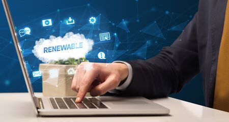 Businessman working on laptop with RENEWABLE  inscription, modern technology conceptの写真素材