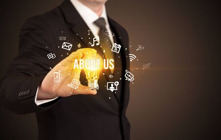 Businessman holding light bulb with ABOUT US inscription, social media conceptの写真素材