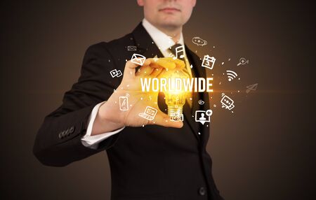 Businessman holding light bulb with WORLDWIDE  inscription, social media conceptの写真素材
