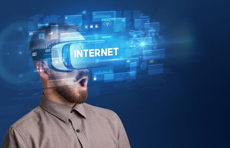 Businessman looking through Virtual Reality glasses with INTERNET inscription, innovative security conceptの写真素材