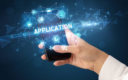 Female hand holding smartphone with APPLICATION inscription, modern technology conceptの写真素材