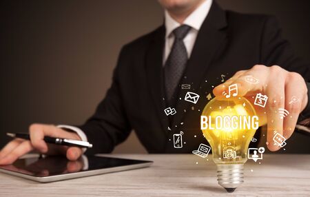 Businessman holding light bulb with BLOGGING  inscription, social media conceptの写真素材