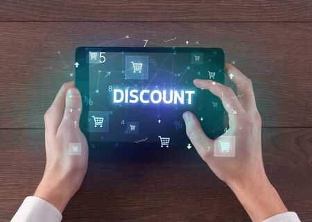 Close-up of a hand holding tablet with DISCOUNT inscription, online shopping conceptの写真素材