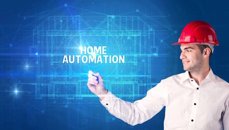 Handsome architect with helmet drawing HOME AUTOMATION inscription, new technology conceptの写真素材