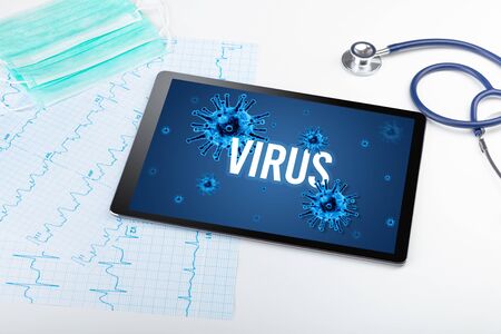 Tablet pc and doctor tools on white surface with VIRUS inscription, pandemic conceptの写真素材