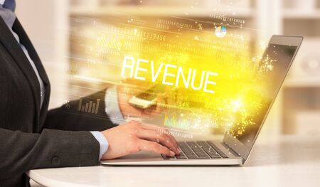 Closeup of businessman hands working on laptop with REVENUE  inscription, succesfull business conceptの写真素材