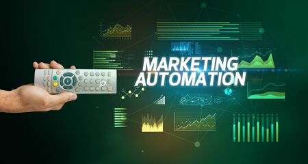 hand holding wireless peripheral with MARKETING AUTOMATION inscription, cyber business conceptの写真素材