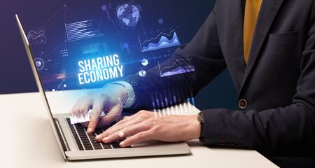 Businessman working on laptop with SHARING ECONOMY inscription, new business conceptの写真素材