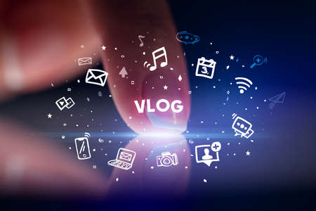 Finger touching tablet with drawn social media icons and VLOG inscription, social networking conceptの写真素材