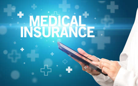 doctor writes notes on the clipboard with MEDICAL INSURANCE inscription, first aid conceptの写真素材