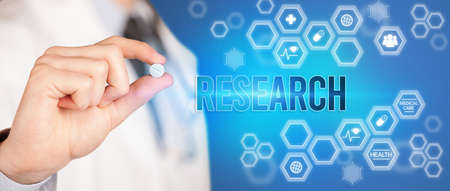 Close-up of a doctor giving you a pill with RESEARCH inscription, medical conceptの写真素材