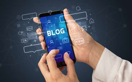 Female hand typing on smartphone with BLOG inscription, social media conceptの写真素材