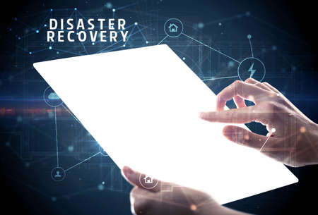 Holding futuristic tablet with DISASTER RECOVERY inscription, cyber security conceptの写真素材