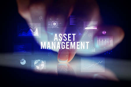 Finger touching tablet with charts and ASSET MANAGEMENT inscription, business conceptの写真素材