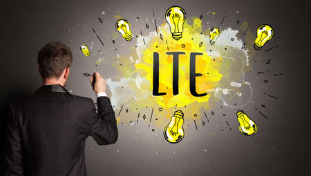 businessman drawing colorful light bulb with LTE abbreviation, new technology idea conceptの写真素材