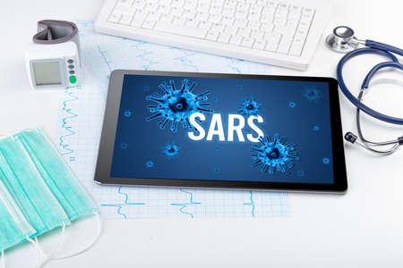 Tablet pc and doctor tools on white surface with SARS inscription, pandemic conceptの写真素材