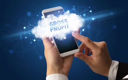 Female hand touching smartphone with GROSS PROFIT inscription, cloud business conceptの写真素材