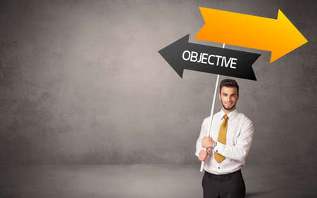 Young business person in casual holding road sign with OBJECTIVE inscription, business direction conceptの写真素材