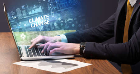 Businessman working on laptop with CLIMATE CHANGE inscription, cyber technology conceptの写真素材