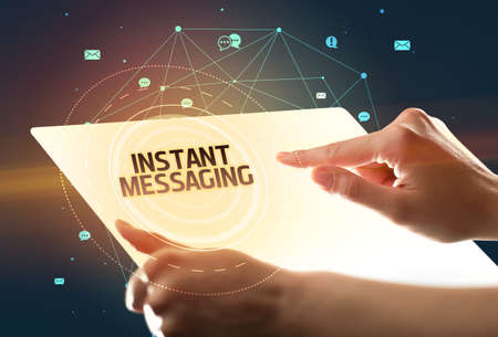 Holding futuristic tablet with INSTANT MESSAGING inscription, social media conceptの写真素材