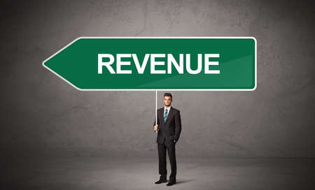 Young business person in casual holding road sign with REVENUE inscription, new business direction...