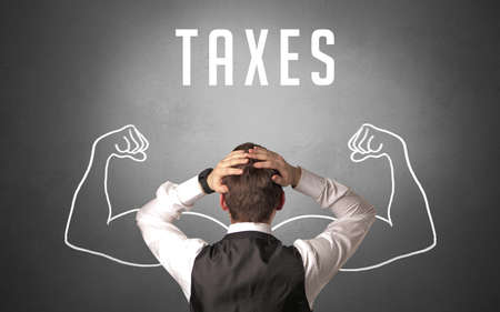 Rear view of a businessman with TAXES inscription, powerfull business conceptの写真素材