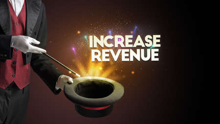 Illusionist is showing magic trick with INCREASE REVENUE inscription, new business model conceptの写真素材