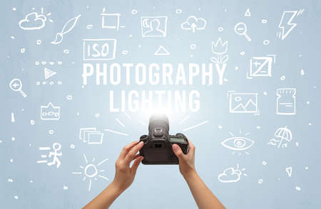 Hand taking picture with digital camera and PHOTOGRAPHY LIGHTING inscription, camera settings...
