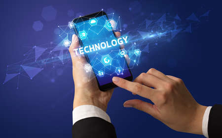 Female hand holding smartphone with TECHNOLOGY inscription, modern technology conceptの写真素材