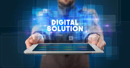 Young business person working on tablet and shows the inscription: DIGITAL SOLUTIONの写真素材