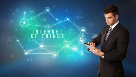 Businessman in front of cloud service icons with INTERNET OF THINGS inscription, modern technology conceptの写真素材