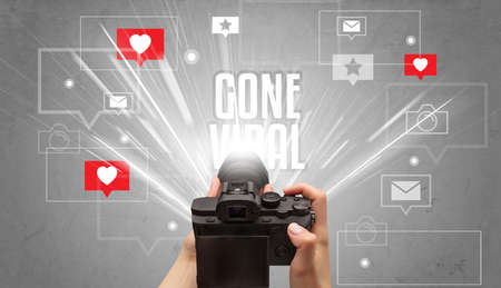 Close-up of a hand taking photos with GONE VIRAL inscription, social media conceptの写真素材