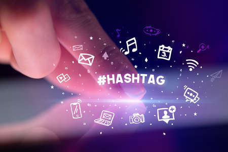 Finger touching tablet with drawn social media icons and #HASHTAG inscription, social networking conceptの写真素材