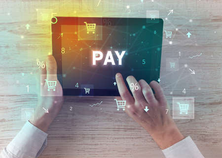 Close-up of a hand holding tablet with PAY inscription, online shopping conceptの写真素材