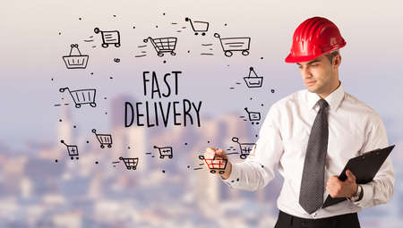 Handsome businessman with helmet drawing FAST DELIVERY inscription, contruction sale conceptの写真素材