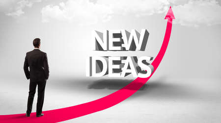 Rear view of a businessman standing in front of NEW IDEAS inscription, successful business conceptの写真素材
