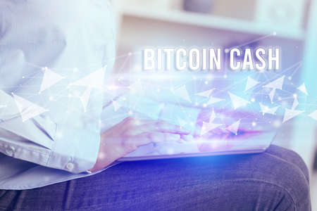 Close up hands using tablet with BITCOIN CASH inscription, modern business technology concept