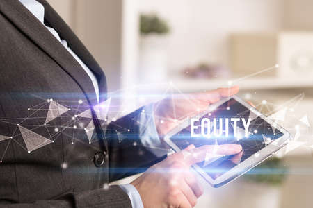 Close up hands using tablet with EQUITY inscription, modern business technology conceptの写真素材